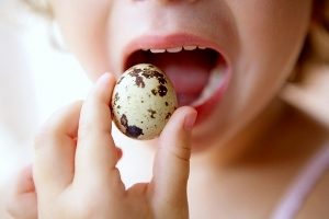 ребёнок пробует на вкус перепелиное яйцо в скорлупе